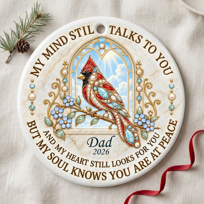 Round ceramic ornament with a red cardinal by a gold arched window, blue flowers, pearls, and a faux marble border.