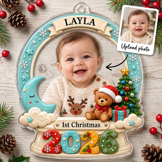 Acrylic snow-globe ornament with baby photo, "1st Christmas", teddy bear, moon, clouds, and big 2026 at the base.