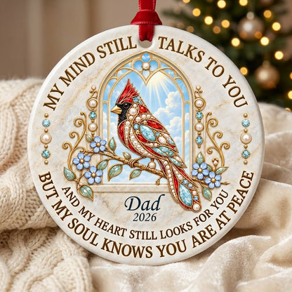 Round ceramic ornament with a red cardinal by a gold arched window, blue flowers, pearls, and a faux marble border.
