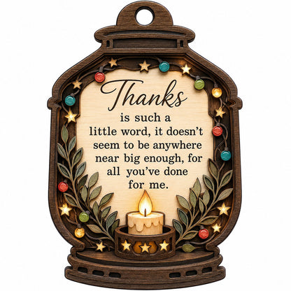 Lantern-shaped wood ornament with candle, colorful fairy lights, leafy branches, and a thank-you quote.