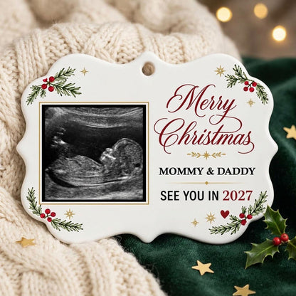 Round ceramic ornament with ultrasound photo, pine branches with red berries, gold starbursts and a red heart icon.