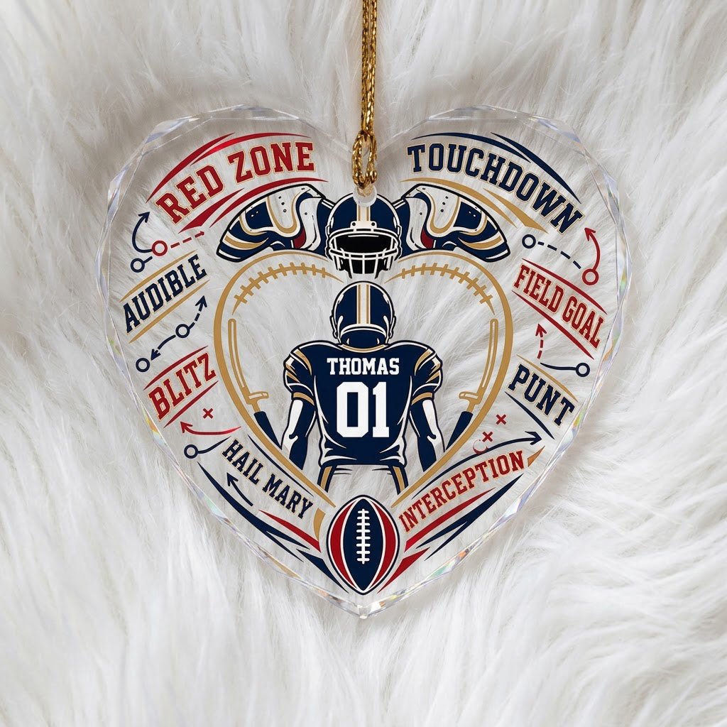 Heart-shaped glass ornament with back-view football player, gold stitched heart frame, football, and play diagram elemen