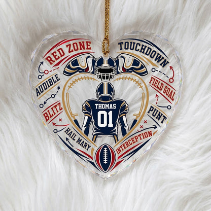 Heart-shaped glass ornament with back-view football player, gold stitched heart frame, football, and play diagram elemen