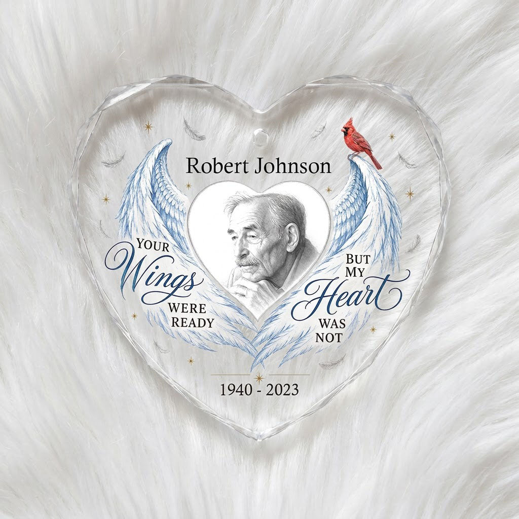 Heart-shaped glass ornament with blue angel wings, red cardinal, and a memorial quote with name and years.