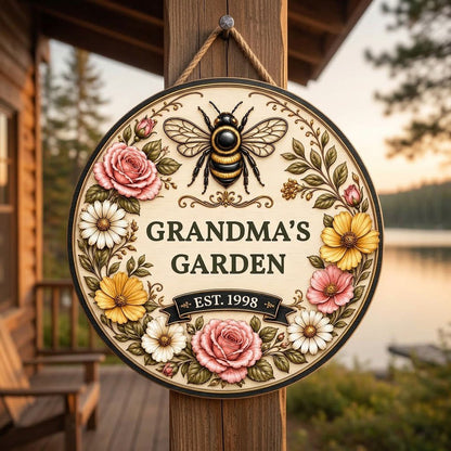 Round wooden sign with 'GRANDMA'S GARDEN', a gold-and-black bee, floral wreath, and EST. year on a light wood background