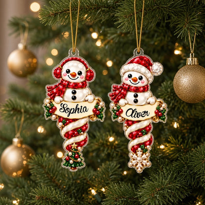 Custom-cut acrylic snowman ornaments with red scarves and scroll banners personalized with a child's name.