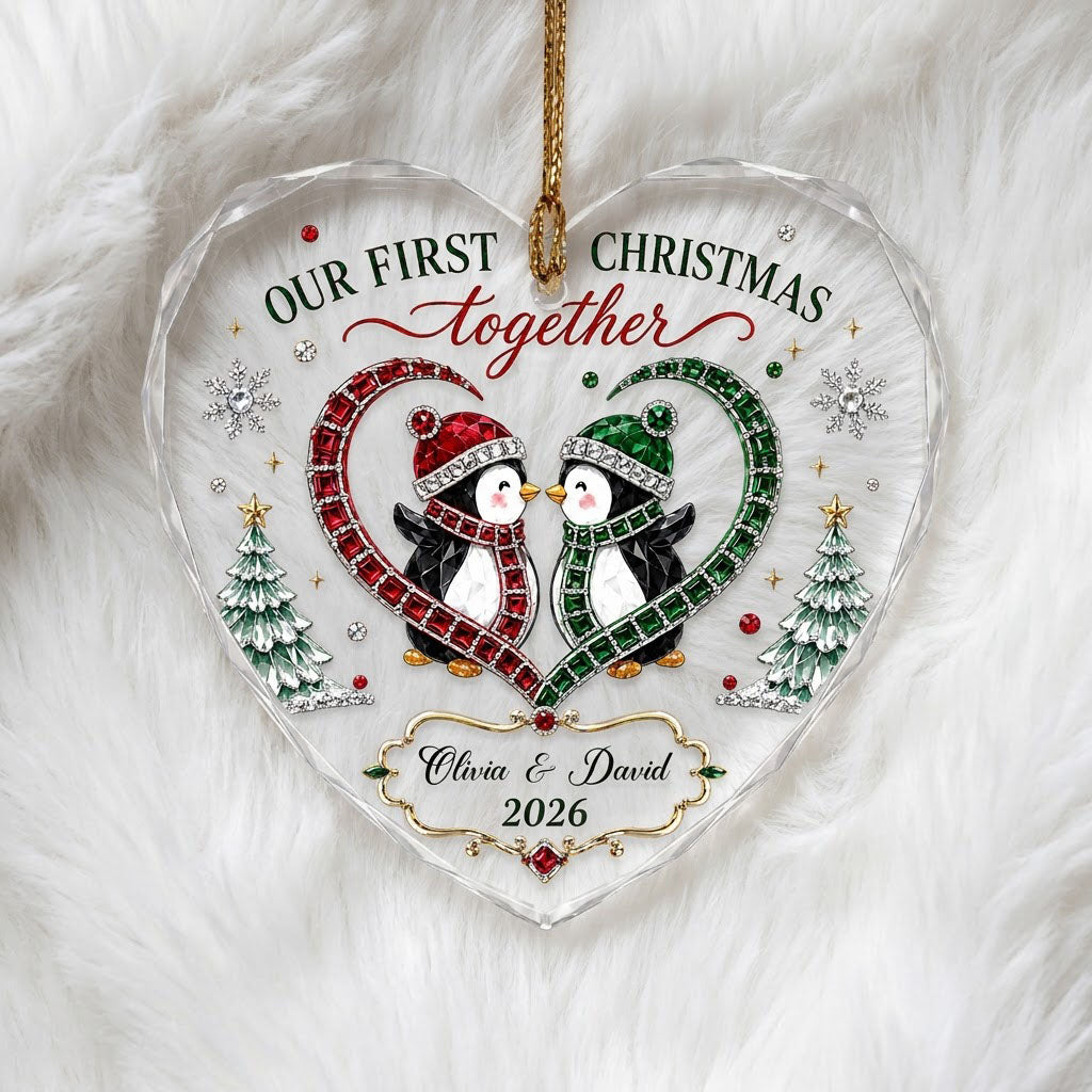 Heart-shaped stained glass suncatcher with two penguins in red and green scarves, jeweled trees, and silver snowflakes