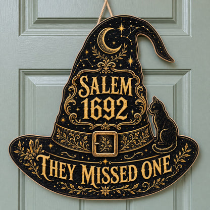 Witch hat-shaped wooden sign with 'SALEM 1692 THEY MISSED ONE', crescent moon, stars, filigree, and a black cat on the b