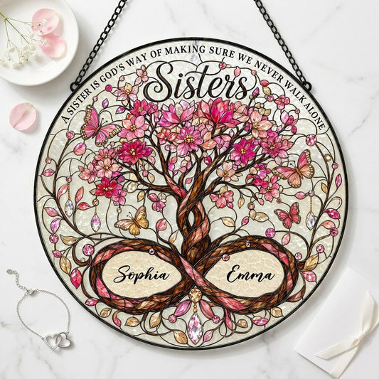 Round stained glass suncatcher with tree of life, pink blossoms, butterflies, and Sisters text with two names.