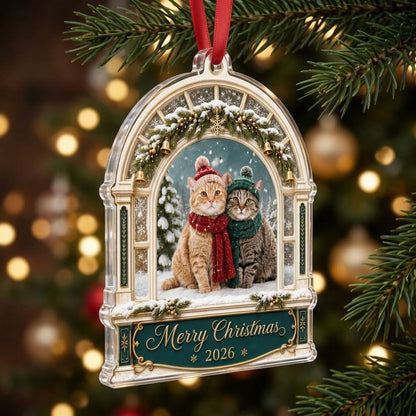Arched window acrylic ornament with pine garland, gold bells, two cats in winter hats and scarves, and a green banner fo