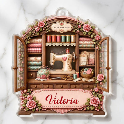 Acrylic ornament shaped like a sewing cabinet with roses, sewing machine, scissors and a pink name banner.