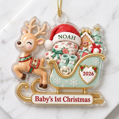 Acrylic ornament of a reindeer pulling a mint-green sleigh with a baby, gifts, and 'Baby's 1st Christmas' text.