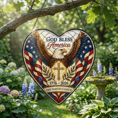 Heart-shaped stained glass suncatcher with a bald eagle over a golden cross and American flag border.