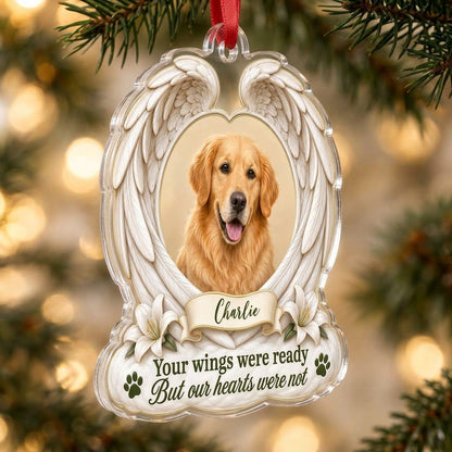 Clear acrylic angel wings ornament with a circular dog photo, white lilies, a dark green paw print, and a name banner.