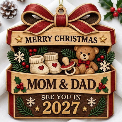 Gift box-shaped wood ornament with red bow, baby booties, teddy bear, and 'Mom & Dad See You In 2027' text.