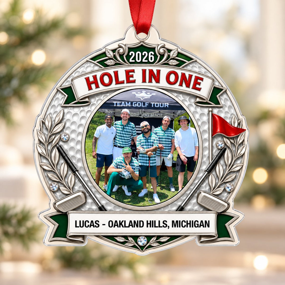 Silver trophy-style golf ornament with laurel branches, crossed clubs, red flag, 2026 and HOLE IN ONE, plus a circular p