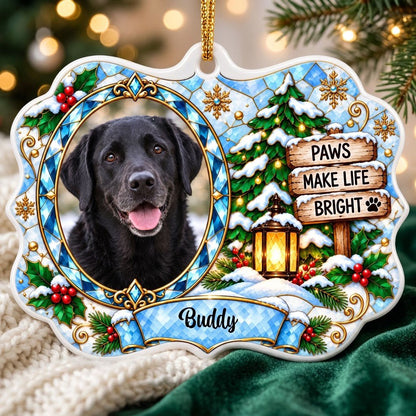 Scalloped ceramic medallion ornament with dog photo, blue stained glass frame, lantern, and Christmas tree in snow.