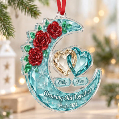 Custom-cut acrylic ornament of a faceted crescent moon with red roses, snowflakes, and two intertwined crystal hearts.