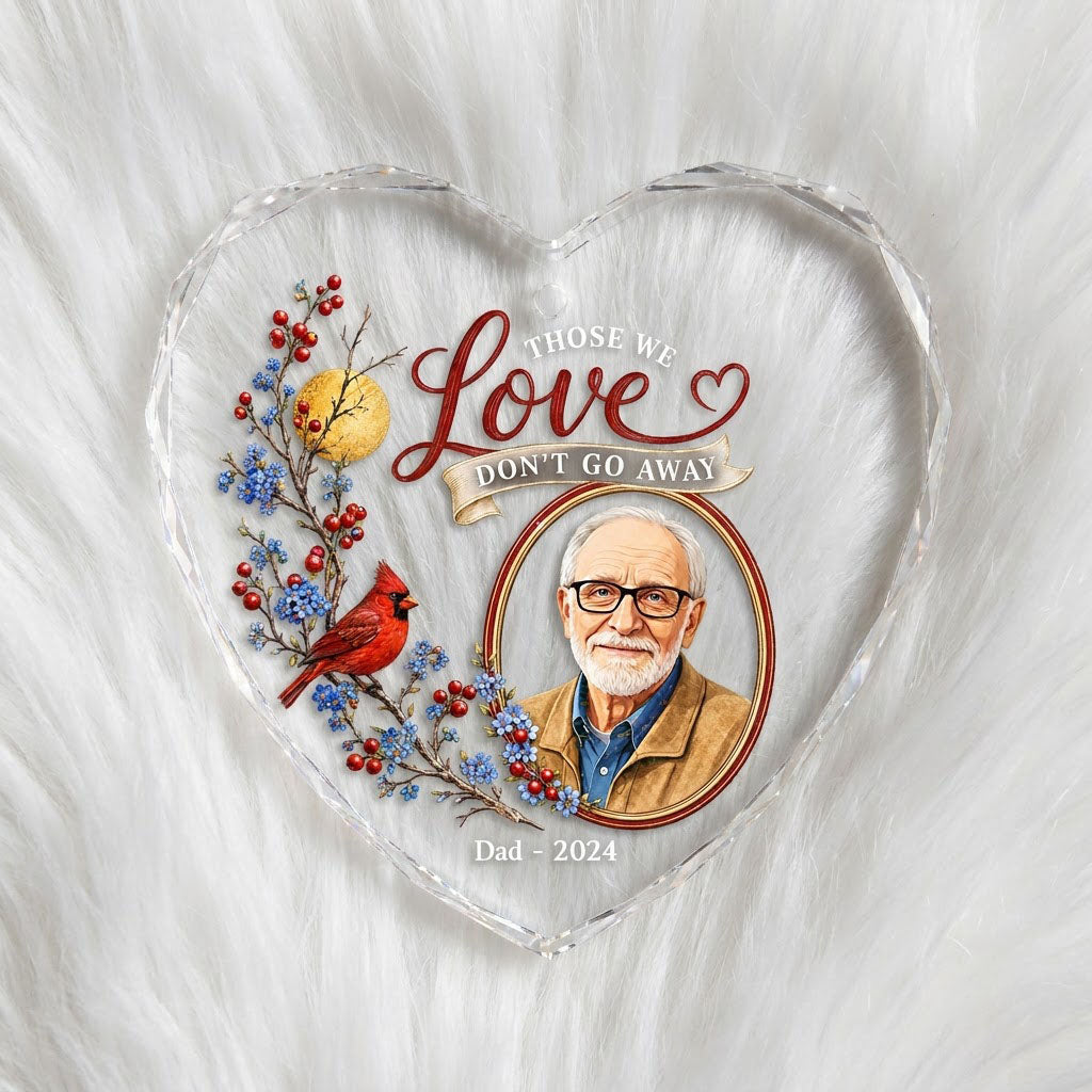 Heart-shaped glass ornament with a red cardinal, golden moon, photo frame and the quote 'THOSE WE Love DON'T GO AWAY'.