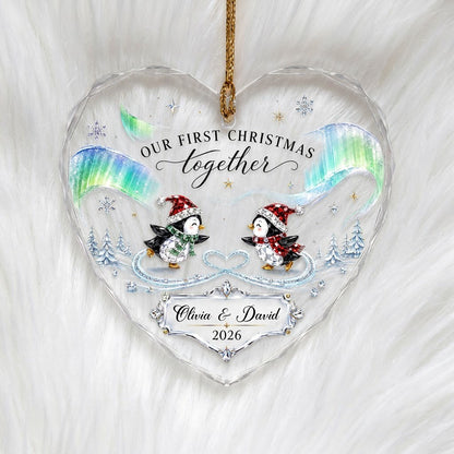 Heart glass ornament with two ice-skating penguins under green and blue aurora with names and date.