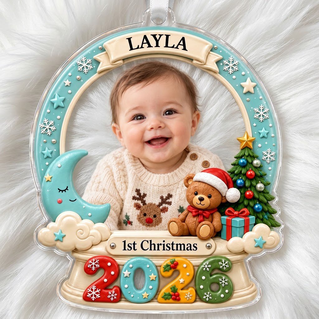 Acrylic snow-globe ornament with baby photo, "1st Christmas", teddy bear, moon, clouds, and big 2026 at the base.