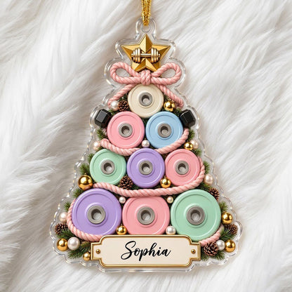 Acrylic Christmas tree ornament of stacked pastel weight plates with a gold star dumbbell and a cream name banner.