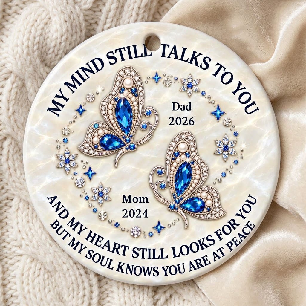 Round ceramic ornament with jeweled blue butterflies, floral rhinestones, and a cream marble background with memorial qu