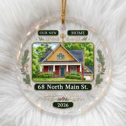Round glass ornament with watercolor house, green and gold banners, gold key, pine branches, and address and year plaque