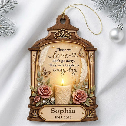 Arched wood-look ornament with lit white candle, two pink roses, butterflies, feathers, and a memorial quote.