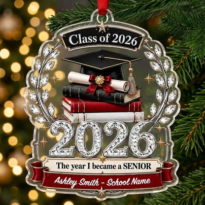 Acrylic ornament shows Class of 2026 text, cap, diploma, jeweled laurel wreath and banners personalized with name and sc