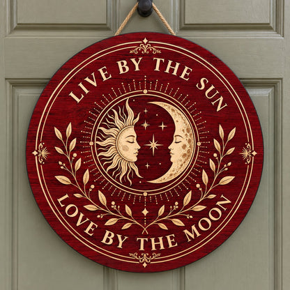 Round wooden sign with sun and crescent moon faces, stars, vines, and the quote Live by the Sun, Love by the Moon.
