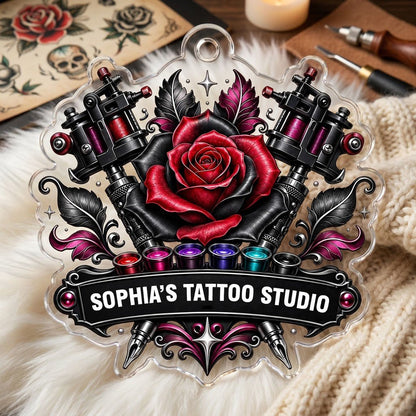 Clear acrylic ornament with red and black rose, crossed tattoo machines, caps, and SOPHIA'S TATTOO STUDIO text.