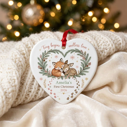 Heart ceramic ornament with sleeping baby fox and fawn in an evergreen wreath with berries and snowflakes.