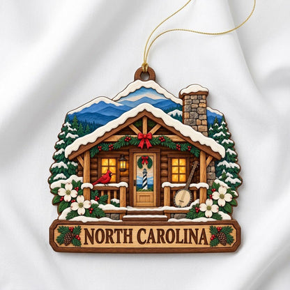Log cabin ornament with NORTH CAROLINA banner, red cardinal, banjo, dogwood flowers, pine trees, and blue mountains.