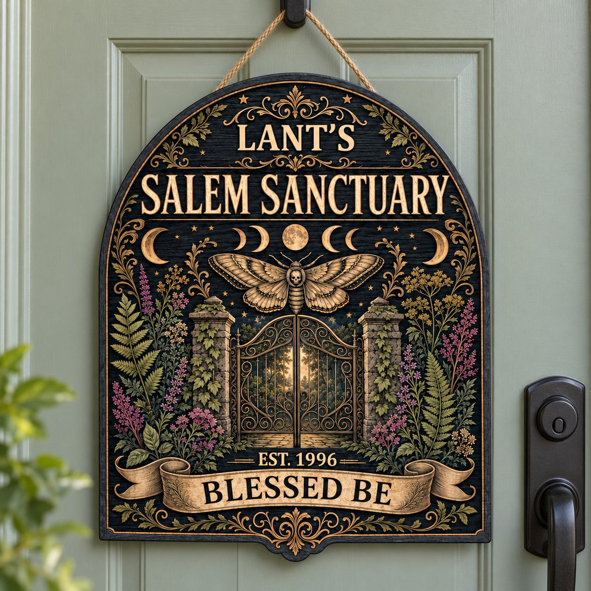 Arch-shaped wooden sign with death's-head hawkmoth, moon phases, wrought-iron gate and ivy on a black background.