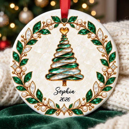 Round ceramic ornament with an emerald jeweled spiral Christmas tree and gold filigree wreath on cream.