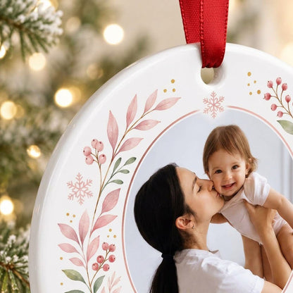 Round ceramic ornament with a photo frame, pink-green botanical wreath, and 'OUR FIRST CHRISTMAS TOGETHER' text.