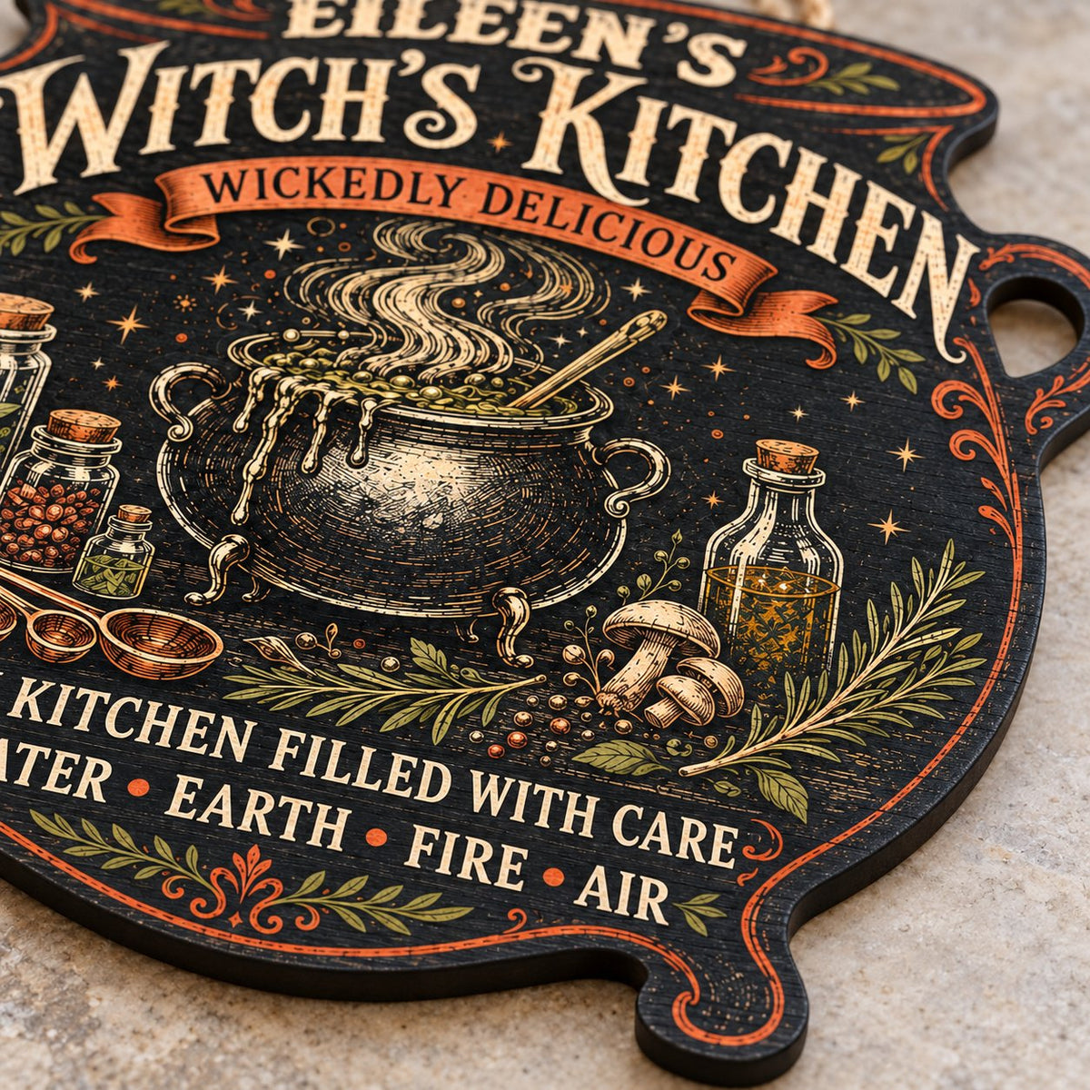 Custom-cut wooden sign shaped like a cauldron with herbs, potion jars, orange scroll and Witch's Kitchen text.