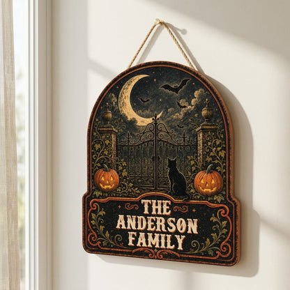 Arched wooden sign with crescent moon, bats, wrought-iron gate, black cat and jack-o'-lanterns with family name.