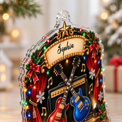 Custom-cut acrylic ornament with crossed red and blue guitars, Merry Christmas marquee, curtains and holly.