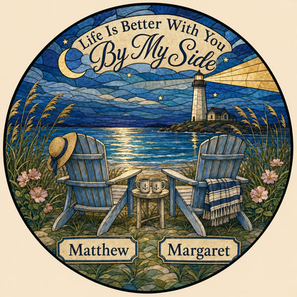 Round stained glass–style suncatcher with two blue Adirondack chairs by water and a lighthouse at night.