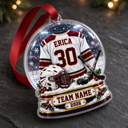 Acrylic snow globe ornament with hockey jersey, helmet, crossed sticks, puck, snowflakes and holly accents.