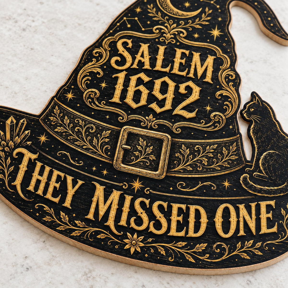Witch hat-shaped wooden sign with 'SALEM 1692 THEY MISSED ONE', crescent moon, stars, filigree, and a black cat on the b