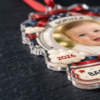 Custom-cut acrylic ornament with baby's photo, patriotic beanie, red bows, stars, and 'Baby's First Christmas' banner.