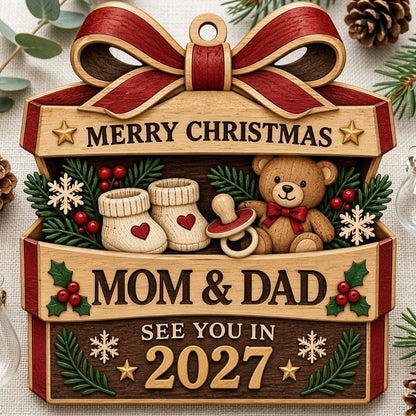 Gift box-shaped wood ornament with red bow, baby booties, teddy bear, and 'Mom & Dad See You In 2027' text.