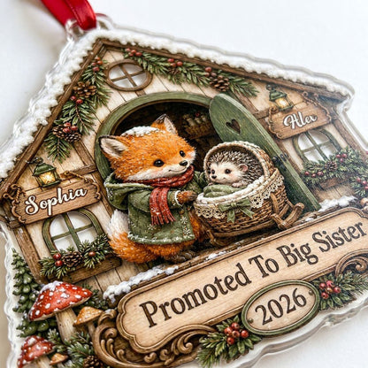 House-shaped acrylic ornament with 'Promoted To Big Sister' and a fox beside a baby hedgehog in a bassinet.