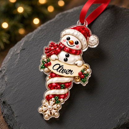 Custom-cut acrylic snowman ornaments with red scarves and scroll banners personalized with a child's name.