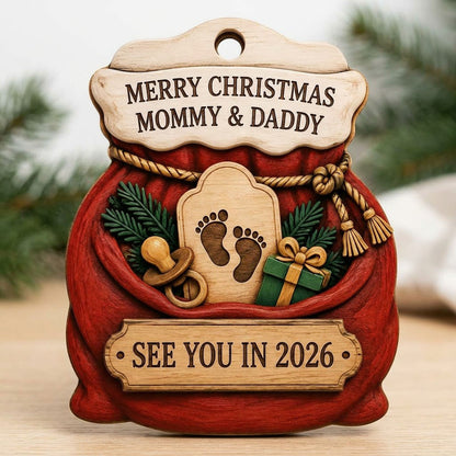 Red Santa sack wood ornament with rope tassels, baby footprints plaque, pacifier, and green gift box.