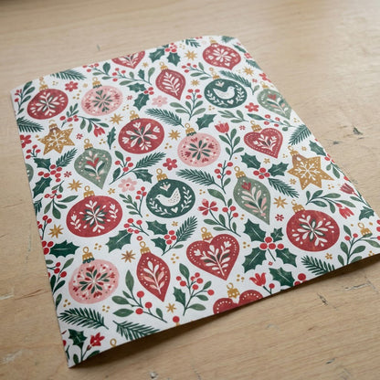 Matte wrapping paper with folk-style red, pink and green ornaments, pine branches, holly and starbursts on cream.