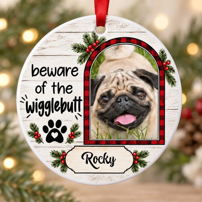 Round ceramic ornament with buffalo plaid photo frame, paw-heart, pine sprigs, and 'beware of the Wigglebutt'.